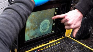 Person pointing at drain camera footage on a laptop screen, illustrating Environ Drainage's professional CCTV drain inspection services.