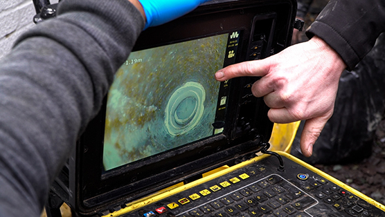CCTV drainage survey monitor displaying drainage inspection results, with hands pointing at the screen, highlighting advanced technology used for diagnosing drainage issues in London.
